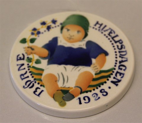 Royal Copenhagen Aluminia fajance Børnehjælpsplatte 1928 Barn i blåt tøj med blomst Oscar Willerup 8,7 cm